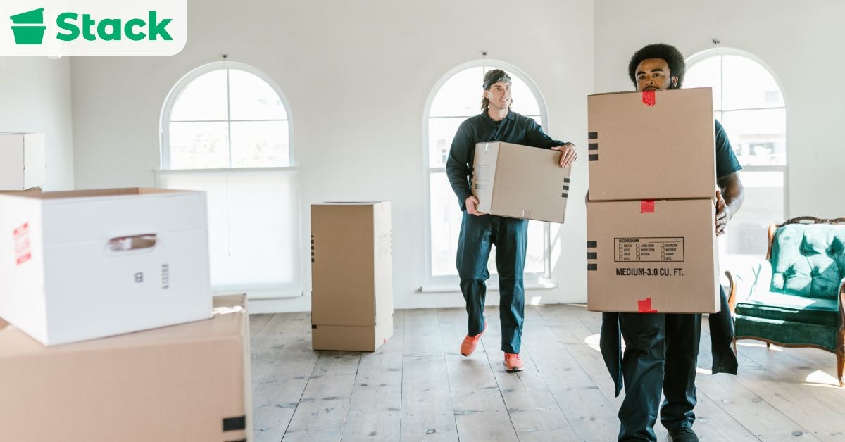Office movers carrying labeled boxes into a new workspace on moving day as part of an organized office relocation.